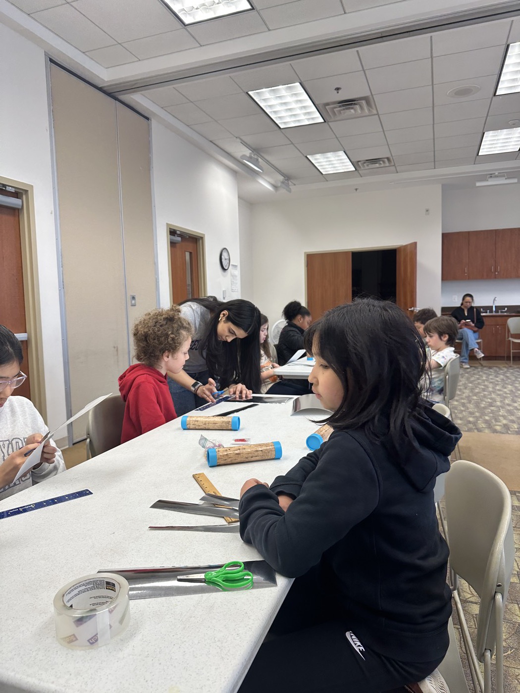 A volunteer leaning in to help students at a workshop table