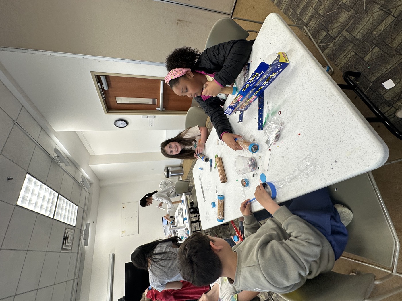 Kids building kaleidoscopes together around a workshop table
