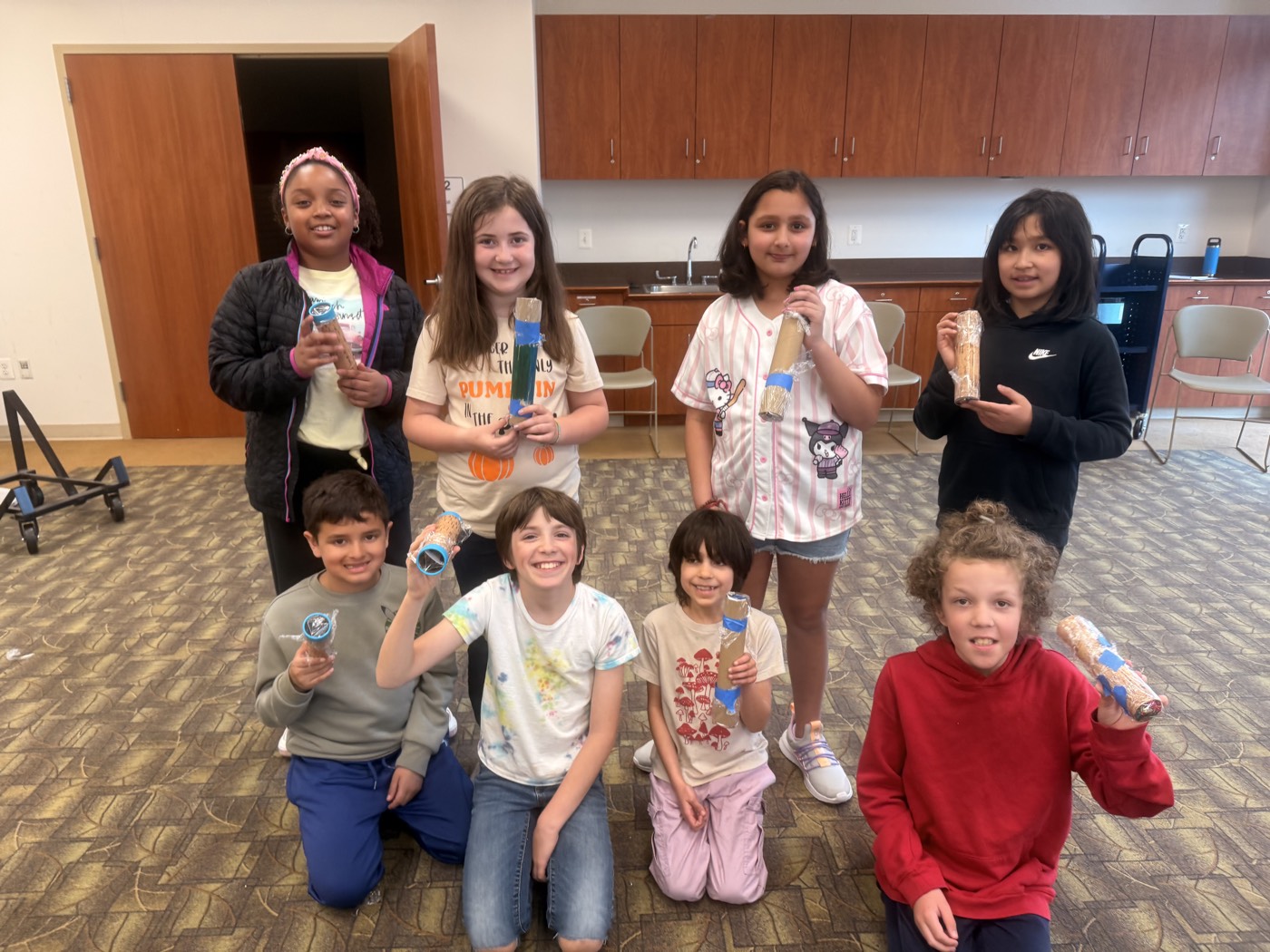 Young workshop participants proudly holding the kaleidoscopes they built
